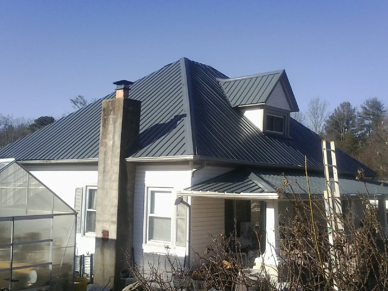 Dark blue standing seam metal roof on a white farmhouse with dormer — Slate & Tile Roof Repair by Roofing Brothers in Woburn