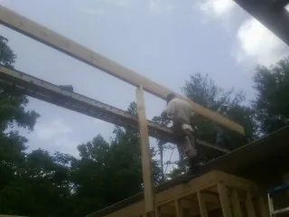 Carpenter setting a ridge beam over a new addition frame — Ice Dam Removal by Roofing Brothers in Woburn