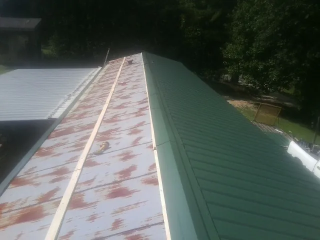 Old rusted panels beside newly installed green metal roofing — Wind Damage Roof Repair by Roofing Brothers in Woburn