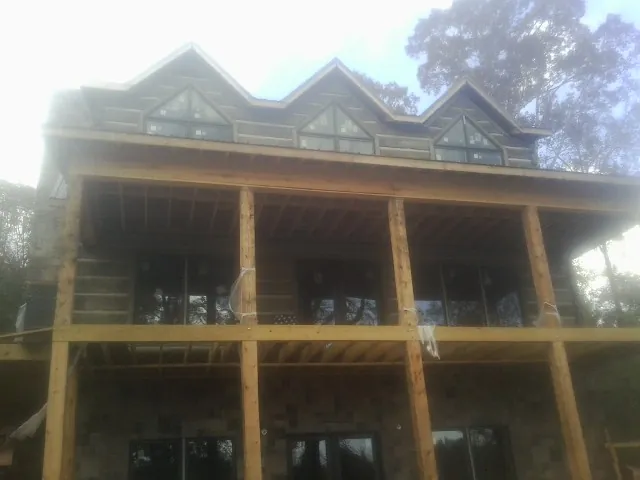Dormers and porch framing on a large log home under construction — Roof Coating work by our crew in Woburn