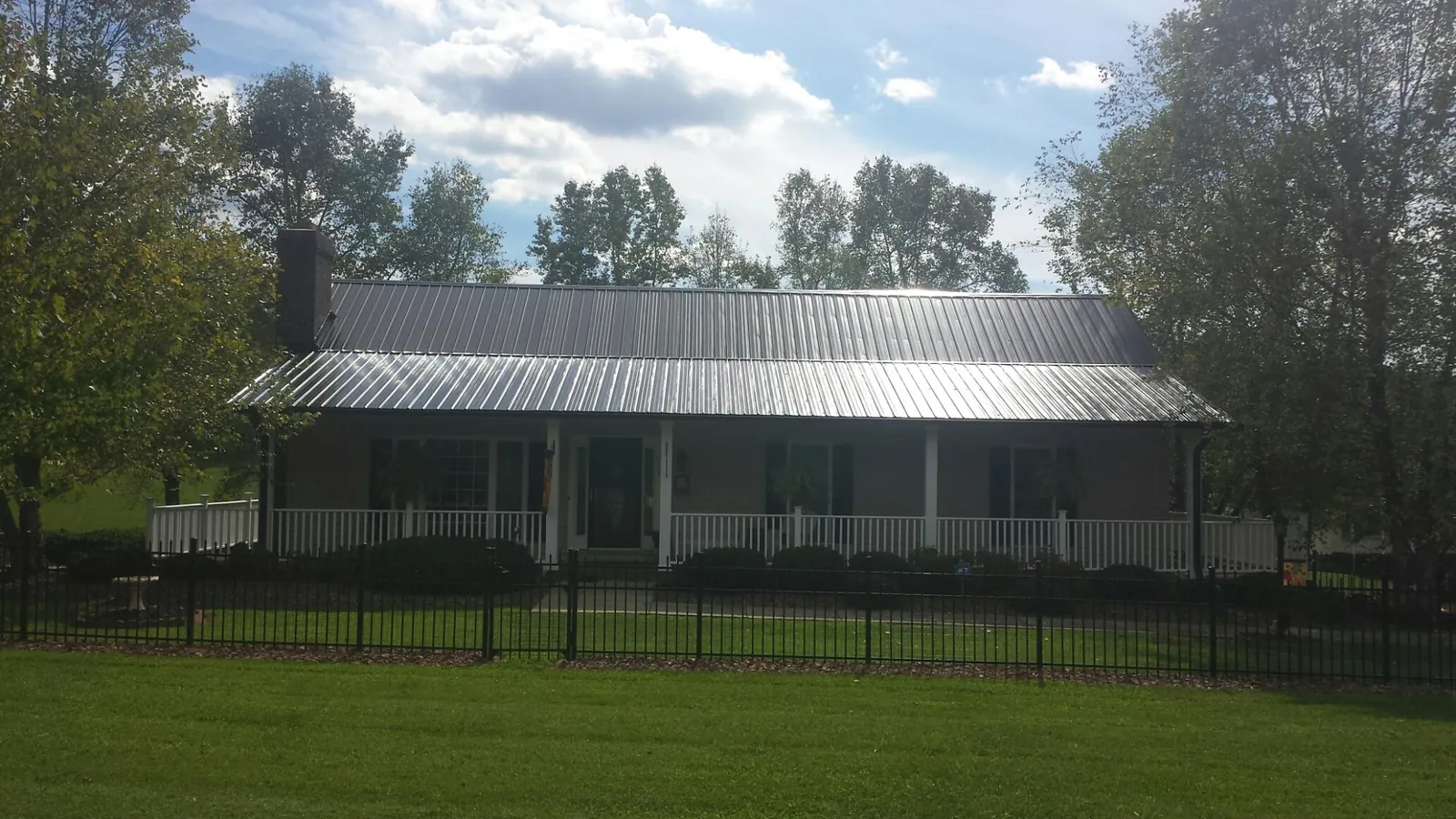 Gray metal roof on a brick ranch with a full width front porch — Gutter Guard Installation work by our crew in Woburn
