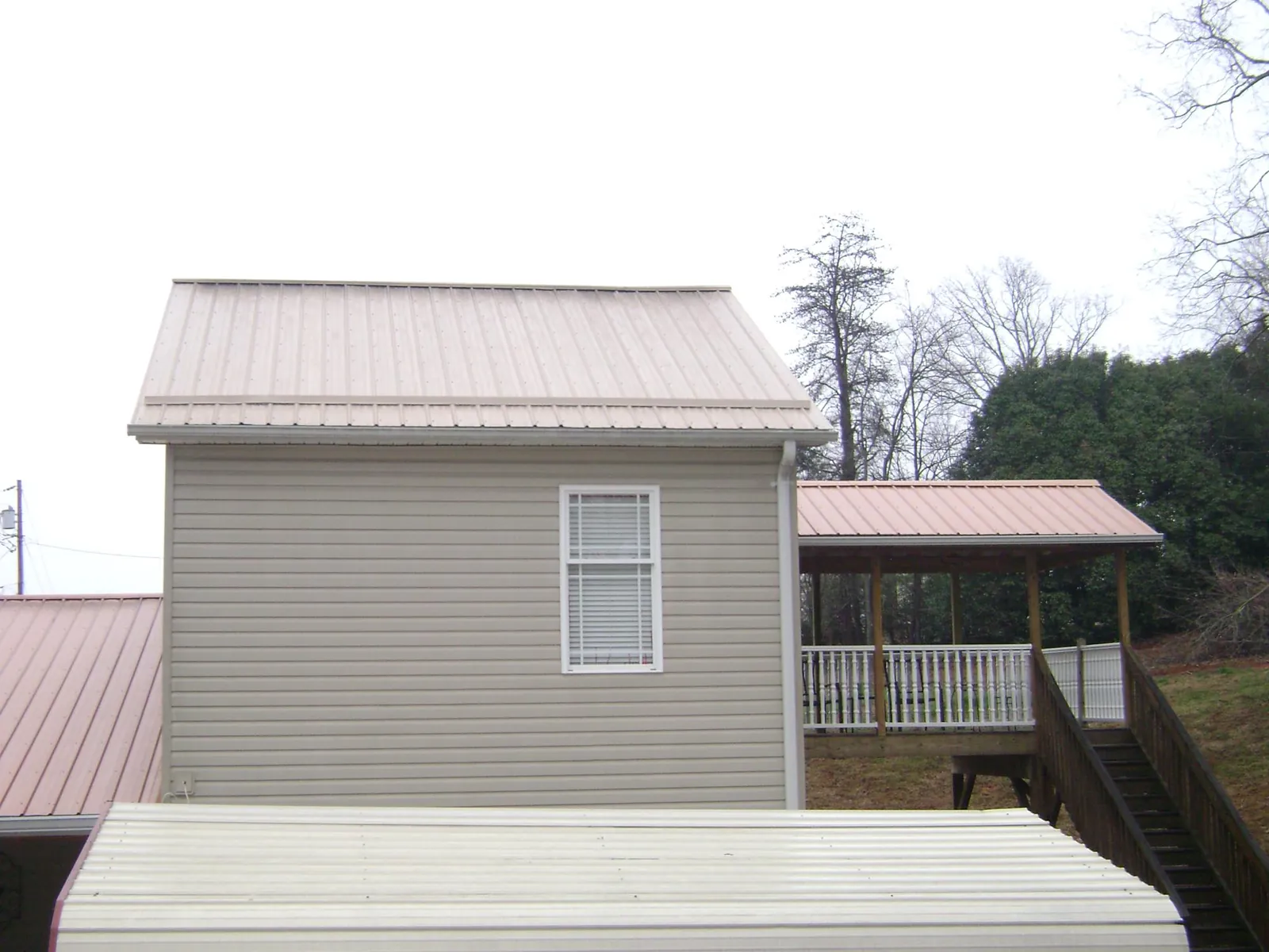 Tan metal roofs on a two story addition and attached porch, from a Roof Replacement job in Woburn
