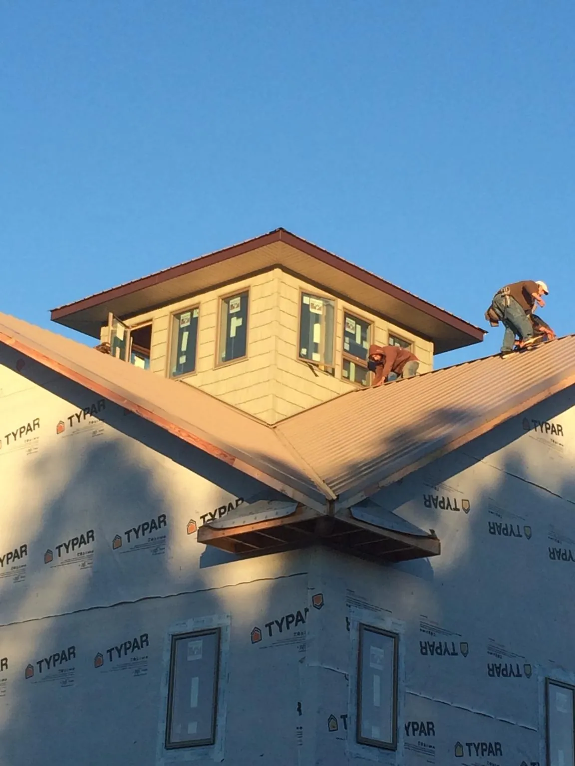 Roofers working around a rooftop cupola on a new metal roof at sunset — Roof Waterproofing in Woburn by Roofing Brothers